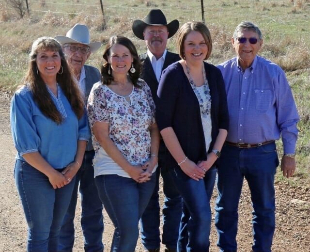 Members of Webber Land Company real estate team standing on a dirt road next to a pasture.